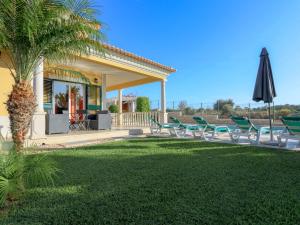 een groep stoelen en een paraplu in een tuin bij Luxury Holiday Villa Alegria Galé Beach, Albufeira in Albufeira