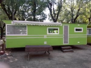a green trailer with a bench in front of it at Camping Sabanell in Blanes