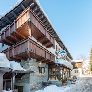 a large building with a wooden roof with snow on the ground at Albergo K2 in Madesimo
