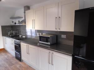 a kitchen with white cabinets and a microwave on a counter at Travellers Rest Apartment in Beverley