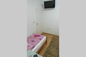a room with a pink bed and a flat screen tv at apartment HOME in Bihać