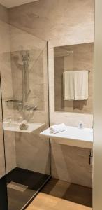 een badkamer met wastafel en douche met spiegel bij Hotel Ciudad de Navalcarnero in Navalcarnero