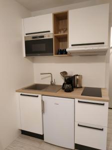 a white kitchen with a sink and a microwave at Cocon d'altitude - Studio avec vue sur les pistes in Les Orres