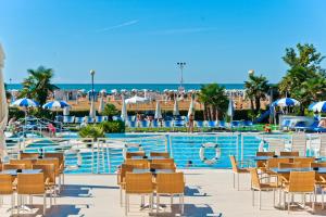 a resort pool with tables and chairs and a swimming pool at Majestic Beach Hotel & Wellness in Bibione