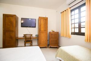 a bedroom with a desk and a tv on the wall at Pousada dos Condes Maresias in Maresias