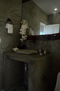 a bathroom with a sink with a mirror and flowers at Hotel Casa Barlovento in Los Naranjos