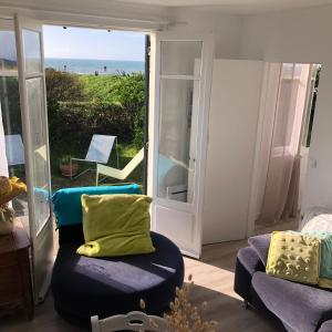 ein Wohnzimmer mit einem Stuhl und einer Tür zum Strand in der Unterkunft Maison de vacances en bordure de mer ! in Batz-sur-Mer