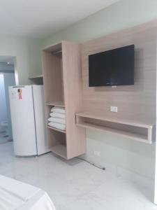 Una cocina con televisión y nevera en una habitación. en CALDAS NOVAS - GO - Apartamento Araras Apart Service - Centro, en Caldas Novas 18 fotos más