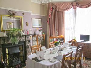 a dining room with a table and a fireplace at Camellia Lodge Guest House in Weston-super-Mare