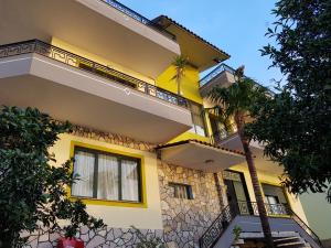 a yellow building with a palm tree in front of it at Villa Meminaj Vlore Sea view and Garden Vlore in Vlorë
