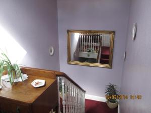 einen Spiegel an einer Wand über einer Treppe mit einem Kinderbett in der Unterkunft Camellia Lodge Guest House in Weston-super-Mare
