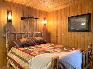 1 dormitorio con 1 cama en una pared de madera en Alaska Creekside Cabins in Seward, en Seward