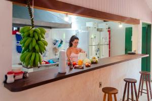 Uma mulher numa cozinha com um monte de bananas. em Clan.Destino Hostel em Ilhabela