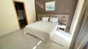 um quarto com uma cama com lençóis brancos e almofadas em Vista Point - Cast Renting em Msida