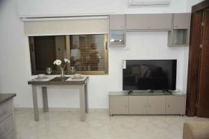 a living room with a television and a table with flowers at Amazing one Bedroom Apartment in Amman Elwebdah 2 in Amman