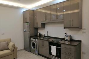 a kitchen with brown cabinets and a washer and dryer at Amazing one Bedroom Apartment in Amman Elwebdah 2 in Amman +11 photos