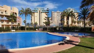- une piscine dans un complexe avec des palmiers et des bâtiments dans l'établissement Apartamento FORTUNA La Manga, à La Manga del Mar Meno