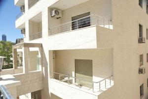 - un bâtiment blanc avec un balcon et une fenêtre dans l'établissement Amazing one Bedroom Apartment in Amman Elwebdah 6, à Amman