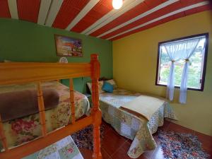 a bedroom with a bunk bed and a window at Chalés Encantos de Cunha Azul in Cunha