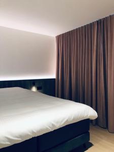 een slaapkamer met een bed en een gordijn bij Suites Le Porte-Bonheur in Brugge