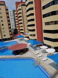 - une grande piscine avec des parasols, des chaises et des bâtiments dans l'établissement CALDAS NOVAS - GO - Apartamento Parque das Aguas Quentes bloco 1 - em frente Clube Privê, à Caldas Novas