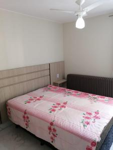a bed with a pink and white blanket with flowers on it at CALDAS NOVAS - GO - Apartamento Parque das Aguas Quentes bloco 1 - em frente Clube Privê in Caldas Novas