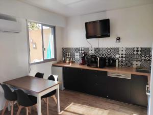 cocina con mesa y TV en la pared en Superbe T1 neuf avec vue mer sur Marinella, en Ajaccio