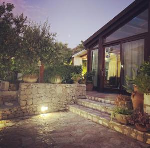 a house with a stone wall and some potted plants at B&B Villa Alba in San Vito lo Capo
