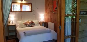 a small bedroom with a bed and two lamps at Hush Boutique Accommodation in Coromandel Town