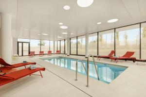 une grande piscine avec des chaises rouges et une piscine dans l'établissement Hyatt Place Paris Charles de Gaulle Airport, à Roissy-en-France