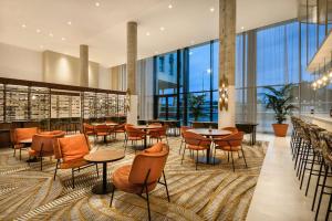 a restaurant with tables and chairs and large windows at Hyatt Place Paris Charles de Gaulle Airport in Roissy-en-France