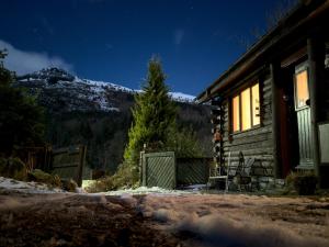 a log cabin with a snow covered mountain in the background at An Carraig Log Cabin in Strathyre