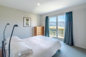 a bedroom with a bed and a large window at Seaview Outlook - Wainui Holiday Home in Wainui