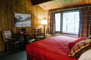 a bedroom with a bed and a table and a window at Glacier Bay Lodge in Gustavus