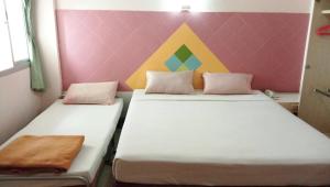 dwa łóżka w pokoju z kolorową ścianą w obiekcie Center Mansion at Hatyai w mieście Hat Yai