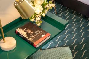 a book on a green table with a lamp and flowers at Hôtel Des Deux-Iles - Notre-Dame in Paris