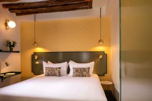 a bedroom with a large white bed with two pillows at Hôtel Des Deux-Iles - Notre-Dame in Paris
