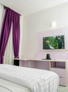 um quarto com uma cama com cortinas roxas e uma televisão em Ocean Park Hotel,Lekki phase 1 em Lekki