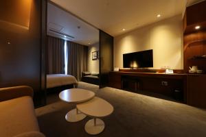 a hotel room with two tables and a bed at Sejong City Osong Hotel in Cheongju