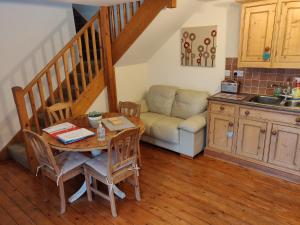 a kitchen with a table and a couch in a room at 3 BR Ensuite Cottage Private Garden Parking Near St Neots in Saint Neots