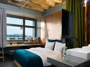 a bedroom with a bed and a desk and a window at 25hours Hotel Bikini Berlin in Berlin