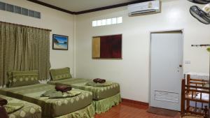 Sala de estar con 2 camas verdes y puerta en Harmony House-SHA Plus, en Islas Phi Phi