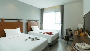 a hotel room with two beds and a desk at Em Oi Boutique Hotel in Nha Trang
