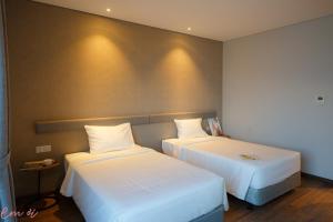 two beds in a hotel room with white sheets at Em Oi Boutique Hotel in Nha Trang