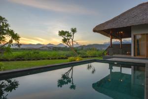 a pool in front of a house with the sunset at Manik Segara Villas in Tegallengah