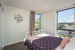 a bedroom with a bed and a large window at Kilmore Apartment - Christchurch Holiday Homes in Christchurch