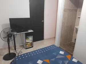 a bedroom with a bed and a television and a fan at Hotel Alférez Real - Jamundí in Jamundí