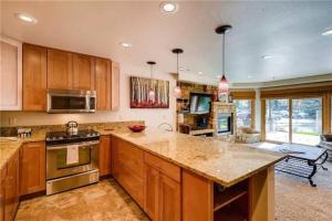 a kitchen with wooden cabinets and a counter top at Ski In, Ski Out 2 Bedroom Vacation Rental In The Heart Of Lionshead Village With Heated Slope Side Pool And Hot Tub in Vail