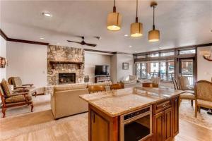 a kitchen and living room with a stone fireplace at Luxury Ski In, Ski Out 2 Bedroom Mountain Residence In The Heart Of Lionshead Village With Heated Slope Side Pool And Hot Tub in Vail