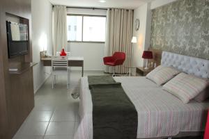 a bedroom with a bed and a desk and a television at Betel Beach Flat Boa Viagem in Recife